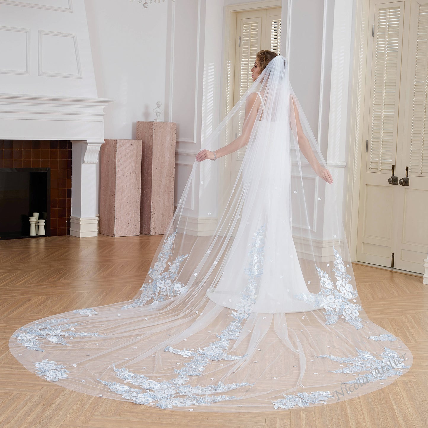 Back view of bride displaying 3m cathedral veil with center lace and blue floral hem. Indoor studio. Nicola Xu Atelier.