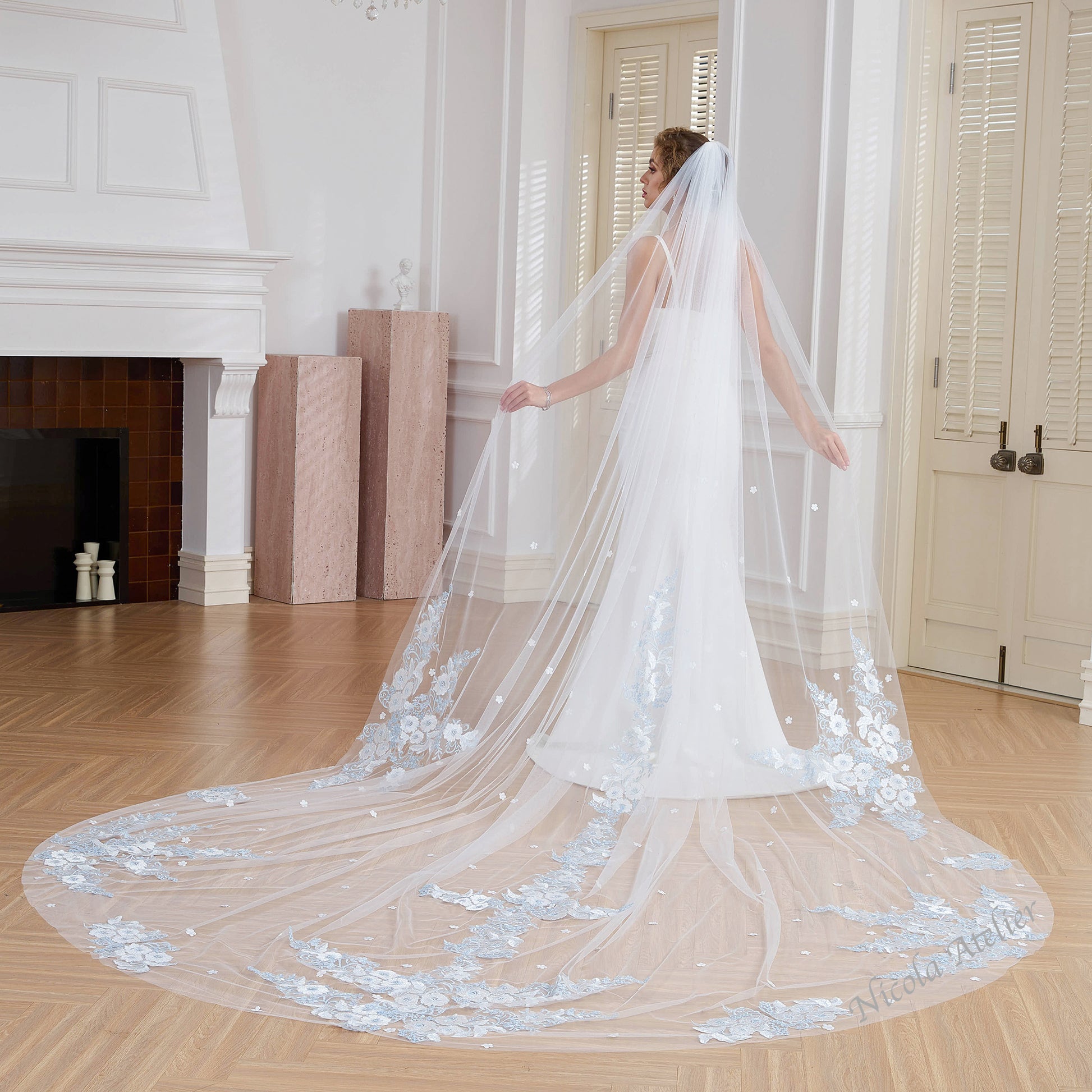 Back view of bride displaying 3m cathedral veil with center lace and blue floral hem. Indoor studio. Nicola Xu Atelier.