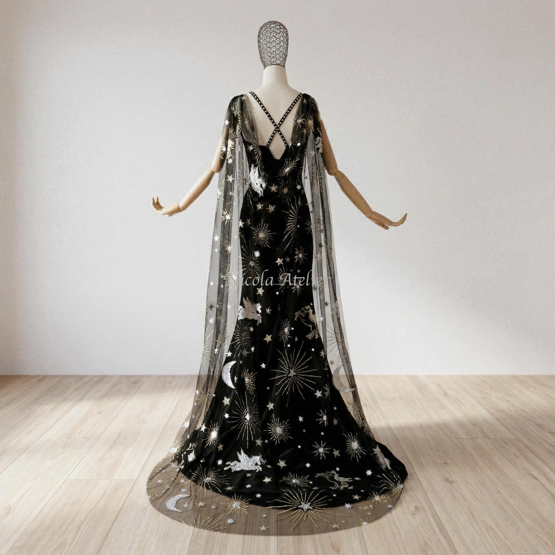 Bridal cloak pooling elegantly on a sunlit hardwood floor. Sheer black tulle with gold embroidered stars and silver moons.