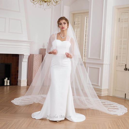 Bride in minimal gown wearing a 2-tier sheer veil with lace train indoors Nicola Xu Atelier.