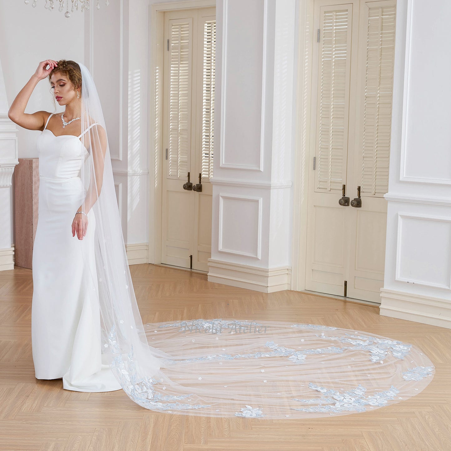 Bride in profile with long cathedral veil trailing on wooden floor showcasing lace trim. Studio. Nicola Xu Atelier.