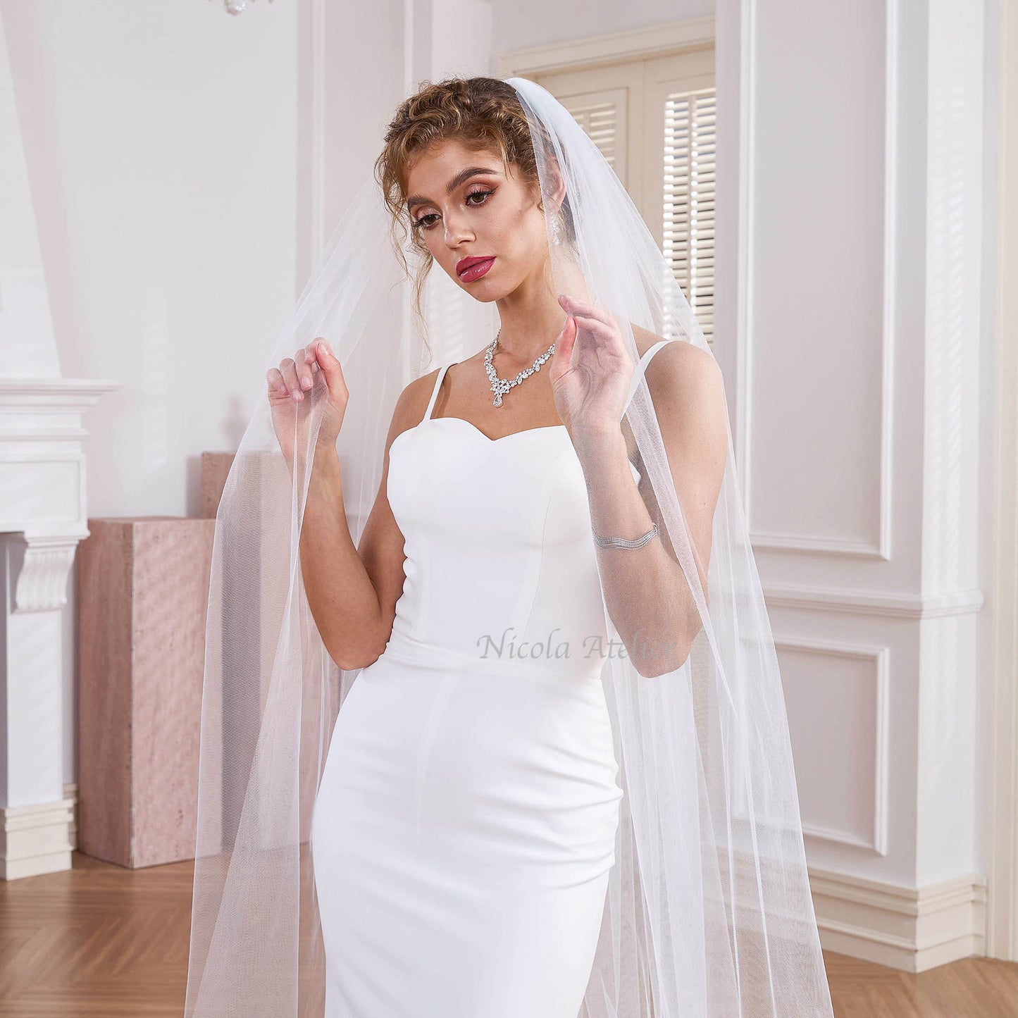 Bride lifting sheer one layer cathedral veil, showing soft drape and transparency,