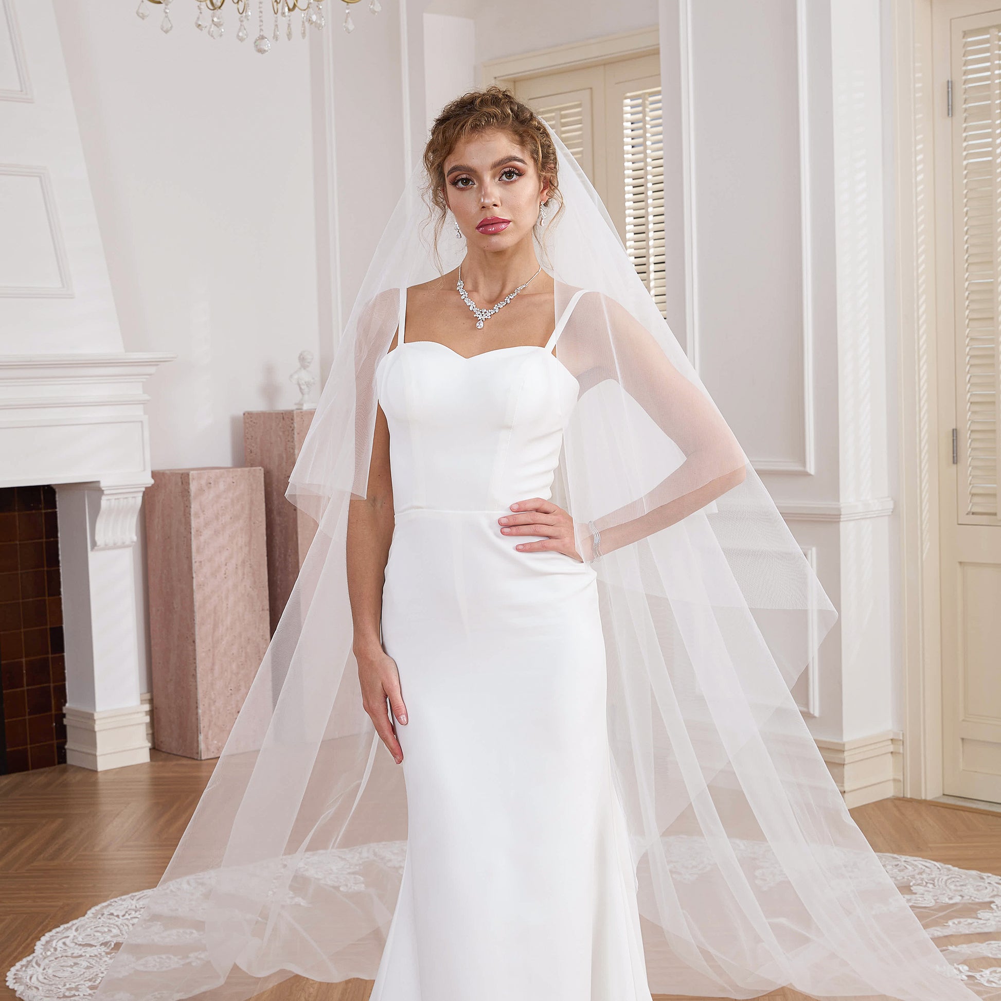Bride posing with a 2-tier drop veil cascading into a wide lace train Nicola Xu Atelier.