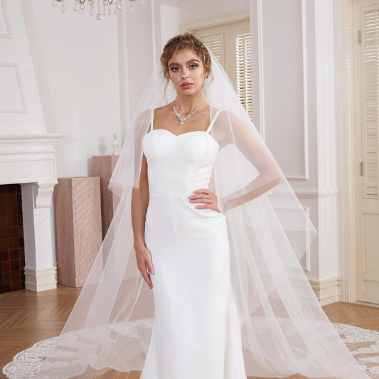 Bride posing with a 2-tier drop veil cascading into a wide lace train Nicola Xu Atelier.