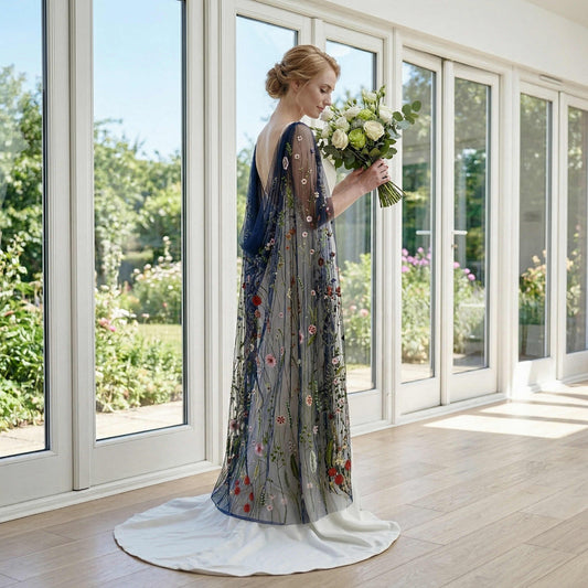 Bride in profile holding a bouquet wearing a soft tulle dark botanical shoulder veil.