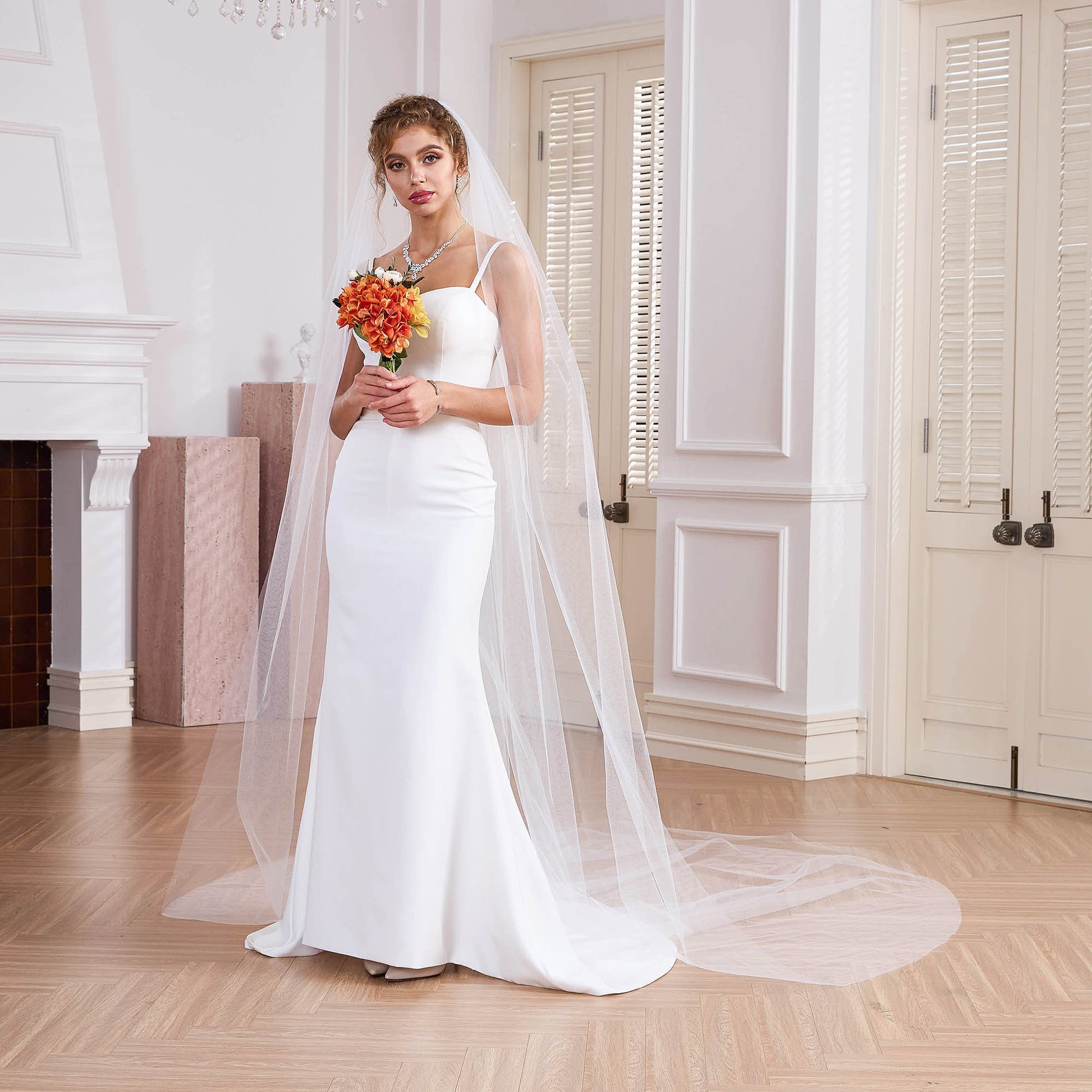 Full length view of bride in satin gown with sheer long veil, indoor minimalist wedding,