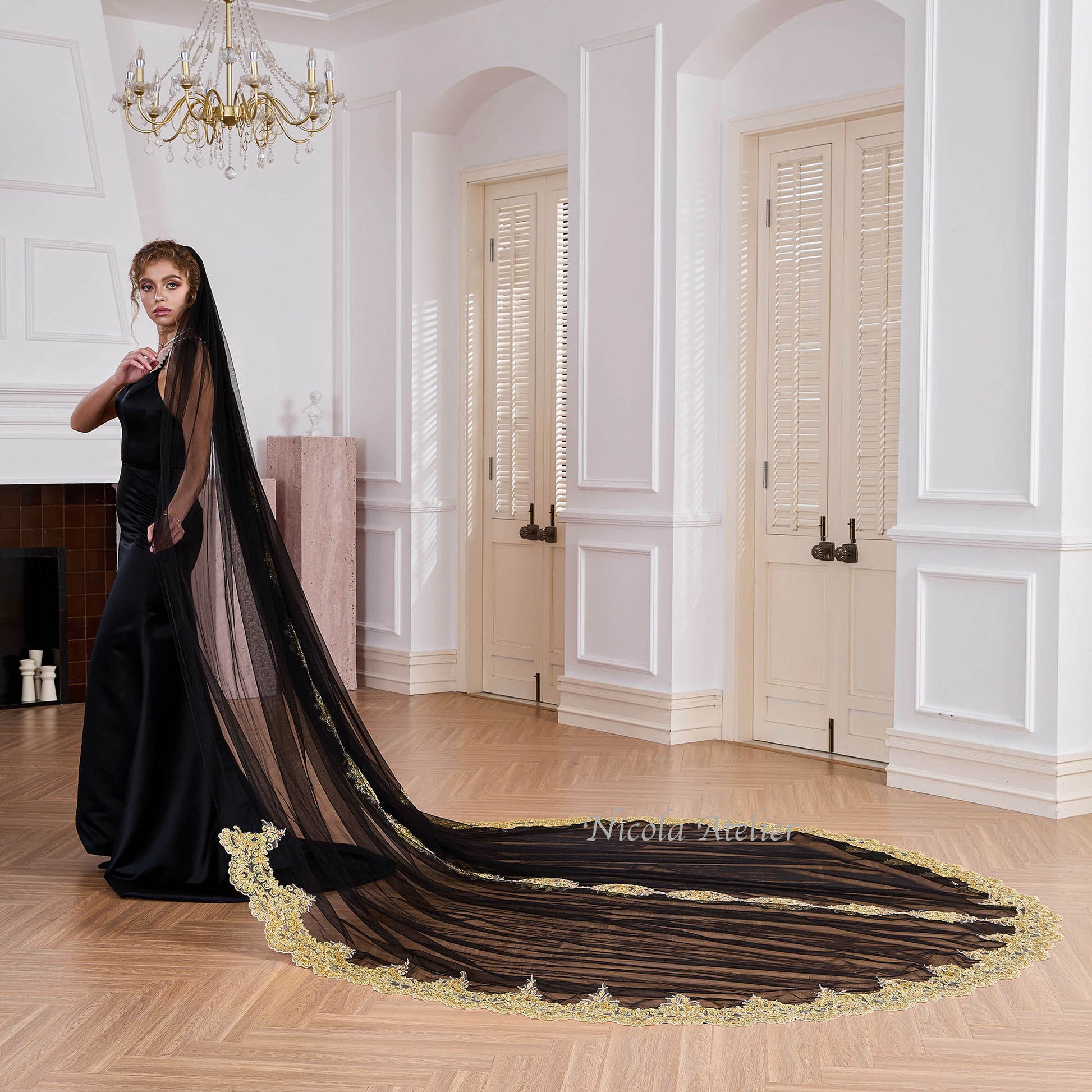 Side profile of bride holding black cathedral veil with gold lace trim in studio Nicola Xu Atelier