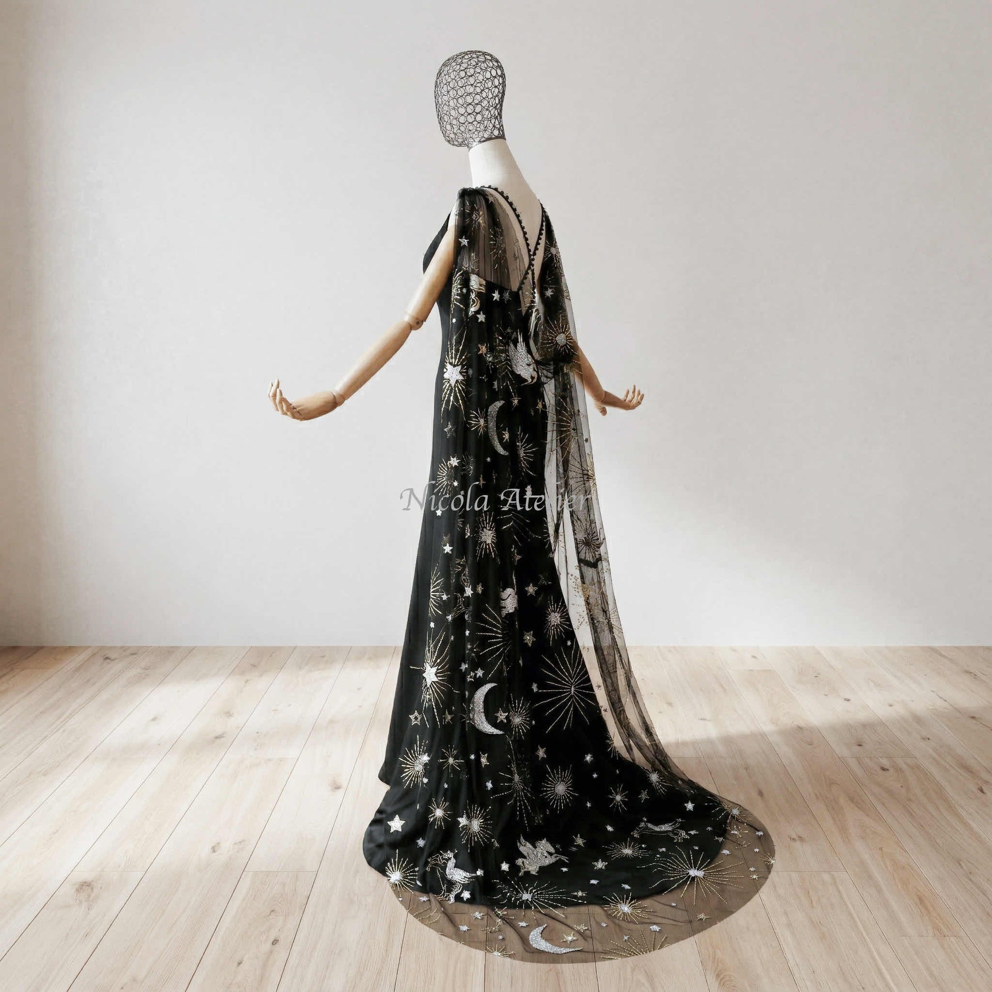 Sunlit room highlighting a draped floor-length celestial shoulder veil. Sheer black tulle with silver pegasus sequins.