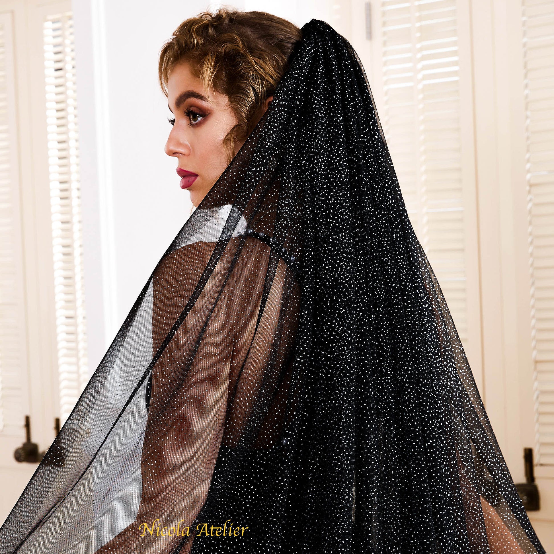 Side profile of a bride wearing a black raw-edge tulle veil with catching silver light by Nicola Xu Atelier.
